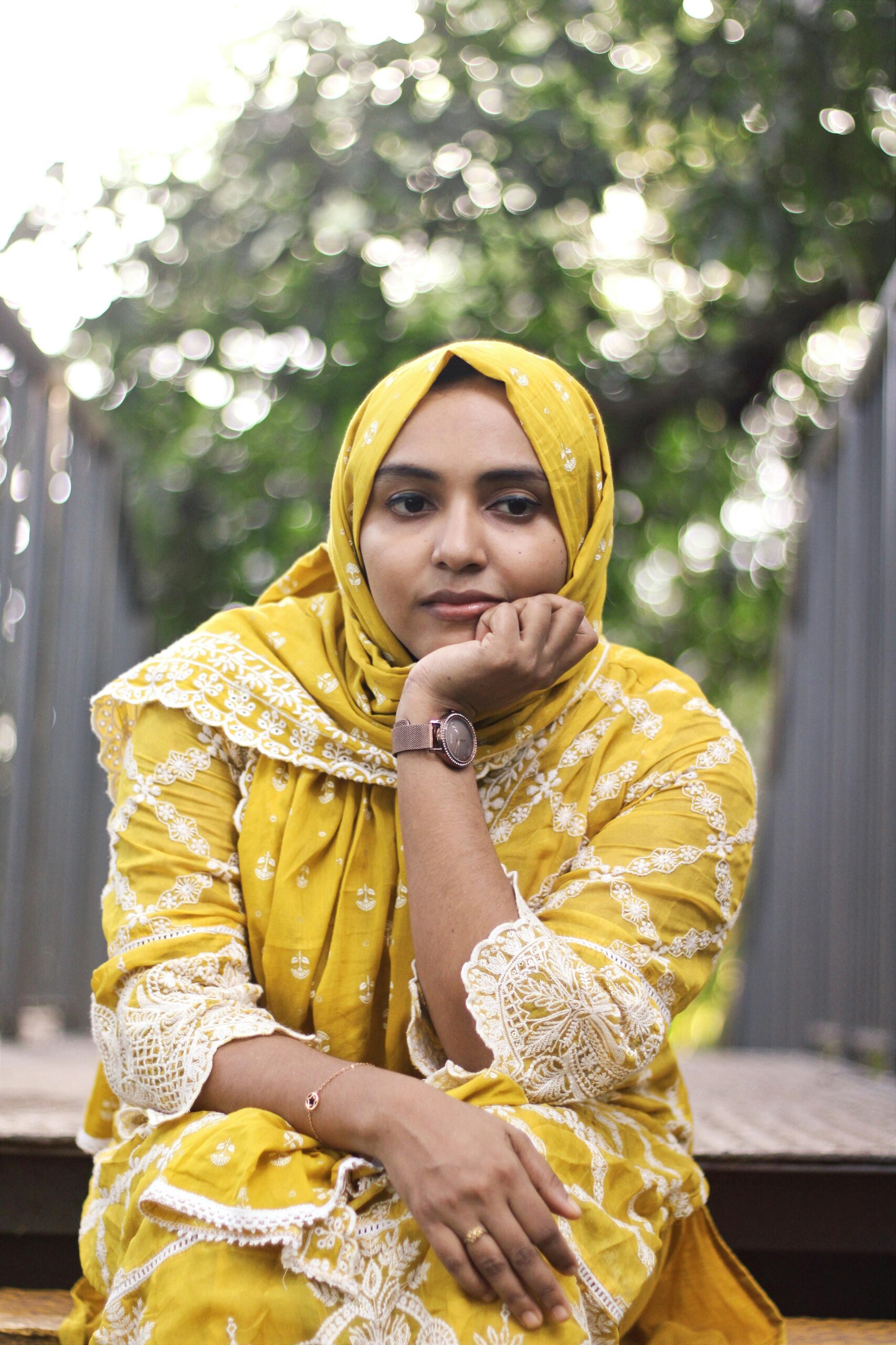 A captivating portrait of a woman in traditional yellow dress outdoors in Nilambur, India.